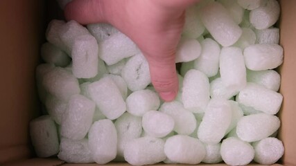 female hand is sorting polypropylene balls for packing fragile parcels in a cardboard box, psychological satisfying, Stress Squeeze, concept of postal item, package, buying goods online
