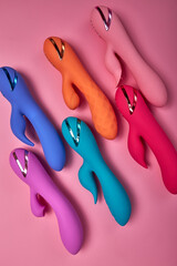 Discover sexier you. Collection of different colorful G-spot vibrators arranged on pink background. Smart gadget and masturbation device. View from above. Place for text. Flat lay. Sex shop concept.