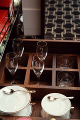 Pull-out drawer filled with glass wine glasses, cups, saucers and spoons