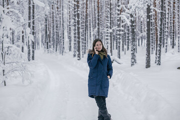 Fototapeta na wymiar Beautiful girl calls a taxi in the winter forest 