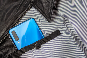 Modern 3d camera smart phone in  jacket pocket. Top view of blue gadget, horizontal orientation