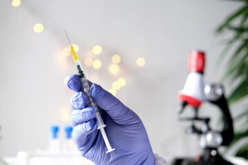 doctor, medic holds in hand a thin syringe for intramuscular injection on a technological blue...