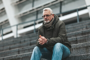 Prayer to God. An elderly man sits outdoors hoping. Thinks alone, depressed.