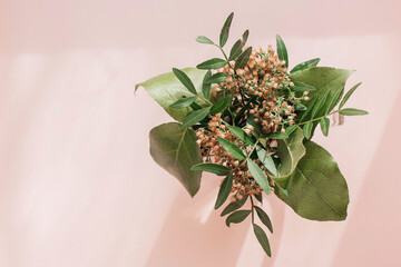 Green bouquet in a transparent cup on a pink background. Greeting card. Copy space.