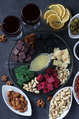 Multicolored gourmet cheese, olives, nuts, honey and sliced lemon on dark background. Appetizer for a wine party. View from above. Vertical format