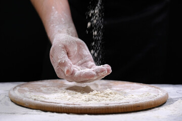 Bakers hand in flour on a black background, close-up. Cooking baked goods