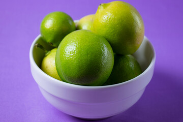 lemons in white bowl on lilac background
