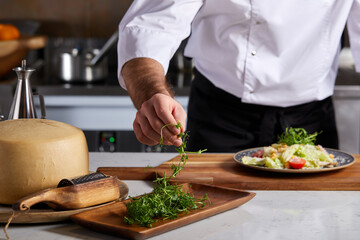 Close-up Cook Hands Taking Some Green To Add At Dish, Focus On Hands. Cropped Male Cook in White Uniform Preparing Cooking Delicious Dish, Showing Master Class