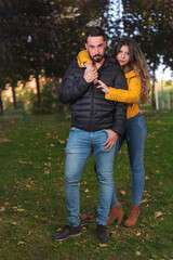 Vertical shot of a young couple in a green park outdoors looking at camera