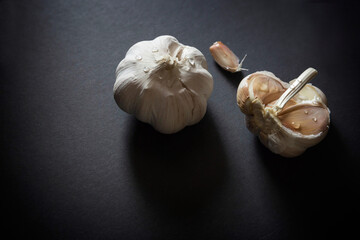 whole organic garlic with segments laying on a black background