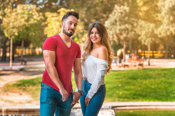 Naklejka premium Shallow focus of a young couple outdoors in a park looking at camera.