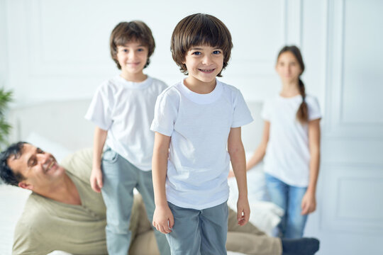 Portrait of happy little latin boy smiling at camera while having fun his father and siblings at home