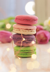 Tasty macaroons and flowers on light background