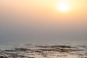USA, California. Sunset over the Pacific Ocean, waves in fog on San Simeon North Shore.