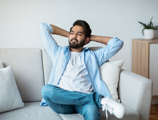 Domestic Rest. Arab Man Leaning Back On Sofa With Hands Behind Head