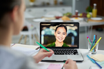 Online study partner. Attractive young female teacher smiling to her students, using video chat app during online lesson. Focus on laptop screen