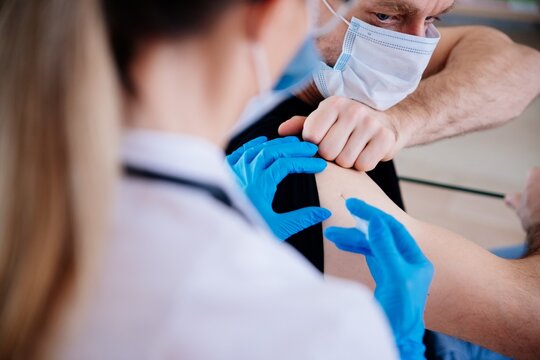 The doctor injects the vaccinations into the patient's arm. Vaccination against COVID-19.