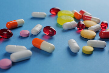 Multicolored pills of various shapes on a blue background