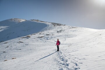 Fototapeta na wymiar Woman hiker on the mountain winter trail. Beautiful snowy day