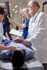 Obraz premium Multiracial Doctor, Surgeons examining x-ray film of patient head for brain, skull injury, emergency help. Medical injury diagnosis and brain injury treatment. Coronavirus COVID 19 quarantine area