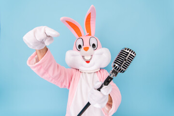 Happy funny kid boy or girl singer or vocalist sings song to retro vintage classic microphone. Easter bunny or rabbit or hare celebrates Happy easter isolated on blue