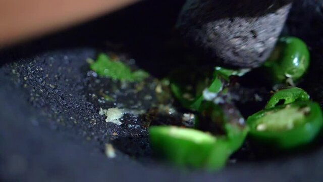 Close-up of hand grinding peppers in a Mexican molcajete