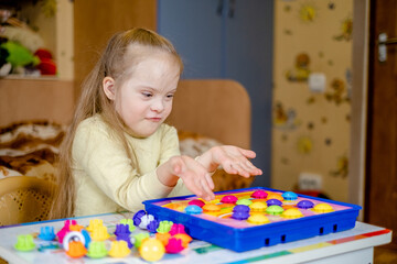 A girl with Down syndrome develops motor skills in her home during the COVID-19 coronavirus pandemic.