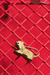 Una reja roja en una pared roja con un candado amarillo con forma de tigre y algunos desgastes