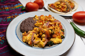 Scrambled eggs and refried beans on white background. Mexican food