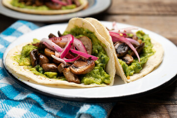 Mushroom and guacamole tacos on wooden background. Mexican food