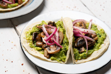 Mushroom and guacamole tacos on white background. Mexican food