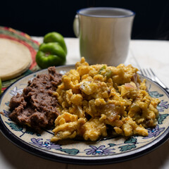 Scrambled eggs with green sauce and refried beans on white background. Mexican food