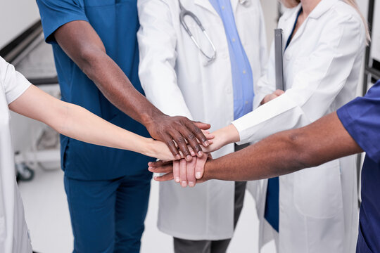 Cropped Multi-ethnic professional doctors men women teamwork coordinate hands fighting covid-19 virus, healthy volunteer doctors team holding hands together