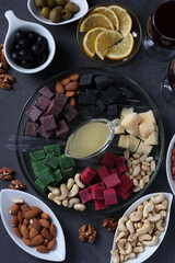 Multicolored gourmet cheese, olives, nuts, honey and sliced lemon on dark background. Appetizer for a wine party. Top view. Vertical format