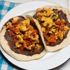 Scrambled eggs and refried beans tacos on white background. Mexican food