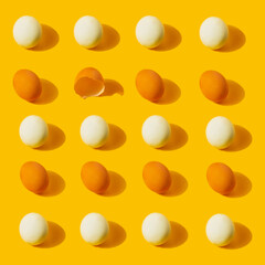 Chicken fresh and boiled eggs pattern with one empty broken eggshell on yellow background. Healthy food or Easter creative minimal concept. Flat lay