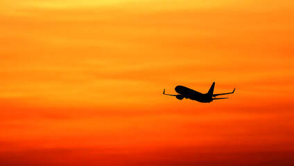 Airliner silhouetted against an orange sunset
