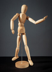 A figure of a wooden man with moving joints on a gray dark background.