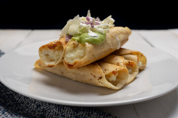 Fried tacos called flautas with guacamole and cabbage on white background. Mexican food