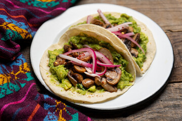 Mushroom and guacamole tacos on wooden background. Mexican food