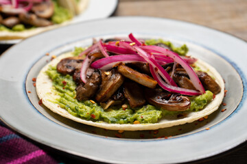 Mushroom and guacamole tacos on wooden background. Mexican food