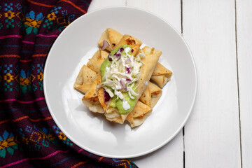 Fried tacos called flautas with guacamole and cabbage on white background. Mexican food