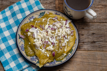 Green enchiladas with fresh cheese and sour cream on wooden background. Mexican food