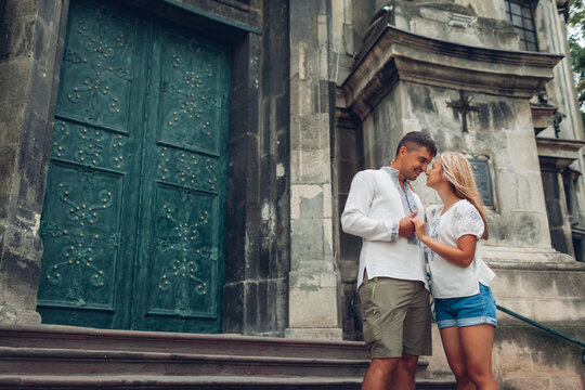 Man and woman in love walking in old Lviv city wearing traditional ukrainian shirts. People hug by dominican cathedral