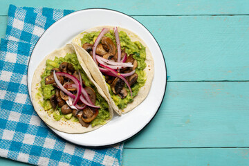 Mushroom and guacamole tacos on turquoise background. Mexican food