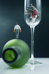 Miniature people. different people are alcoholics at the bottom of a wine glass. the concept of the problem of alcoholism in society