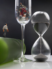 miniature people. man addicted to alcohol is walking on a bottle against the background of a glass with ruined lives. the problem of alcoholism in society