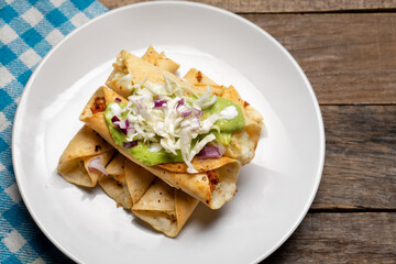 Fried tacos called flautas with guacamole and cabbage on wooden background. Mexican food