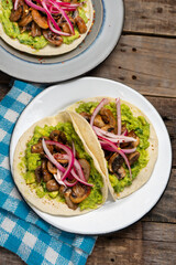 Mushroom and guacamole tacos on wooden background. Mexican food