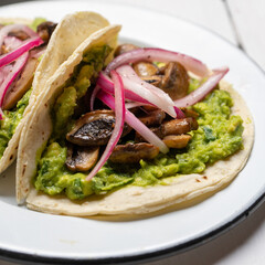 Mushroom and guacamole tacos on white background. Mexican food